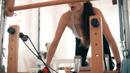 Woman practices pilates with the reformer equipmentの写真素材