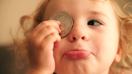 Cute little girl plays with a bitcoin token or coin. Cryptocurrency noob conceptの写真素材