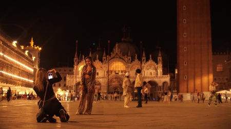 VENICE, ITALY - MAY 26, 2023. Young women make photos on famous Piazza San Marco or St Marks Square in the eveningのeditorial素材