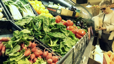 GRENOBLE, FRANCE - JUNE 30, 2023. Senior woman buys fresh vegetables in a local farm food storeのeditorial素材