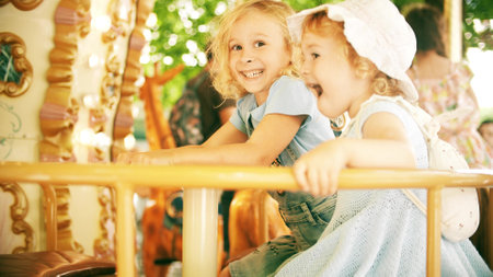 Happy little girls ride a retro carousel on a sunny summer day in Grenoble, Franceの写真素材