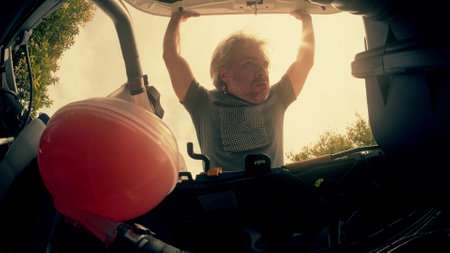 Funny worried man opens hood of his broken car. Unprofessional person or problem conceptの写真素材