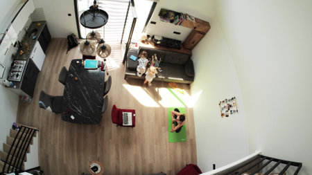Kids play while their mom attends an online yoga class at home, overhead viewの写真素材
