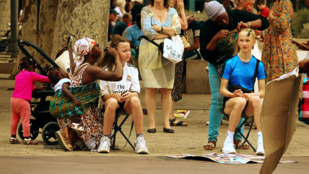 MARSEILLE, FRANCE - AUGUST 9, 2023. Black women making African hairstyles in the streetのeditorial素材