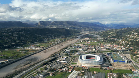 NICE, FRANCE - MARCH 10, 2024. Aerial shot of Saint-Isidore city district involving the Allianz Riviera football arena and the Var Riverのeditorial素材