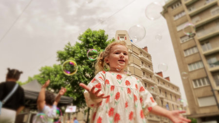 Little girl plays with soap bubbles in the streetの写真素材