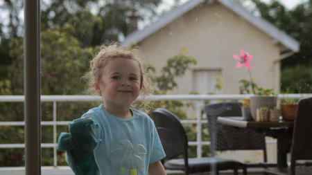 Girl cleans big terrace window at home