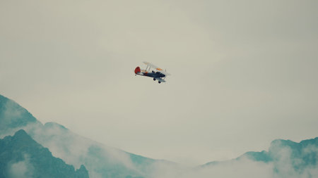 Retro propeller biplane airplane flies over the French Alps mountainsの写真素材