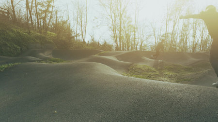 Unknown kids and adults ride on pumptrack or pump track at sunsetの写真素材
