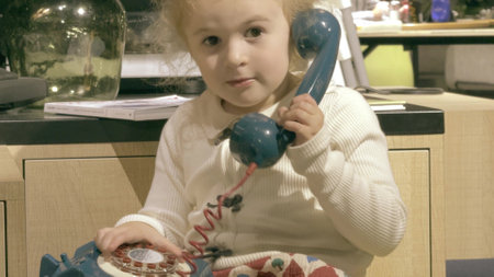 Funny little girl uses blue vintage landline telephoneの写真素材