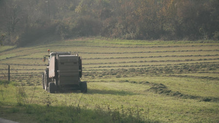 A tractor with hay baler or hay maker trailer in the fieldの写真素材