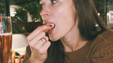A beautiful brunette woman enjoys a chocolate candy and a glass of beverageの写真素材