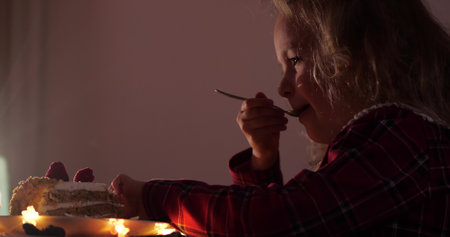 A girl eats the Christmas raspberry cake in the evening, close-up