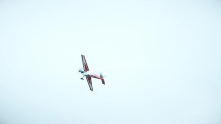 Aerobatic airplane performing stunt with smoke trail in the skyの写真素材