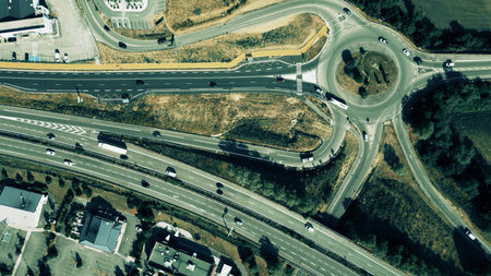 Aerial shot of a roundabout connected to a highway interchange with moving cars and trucks