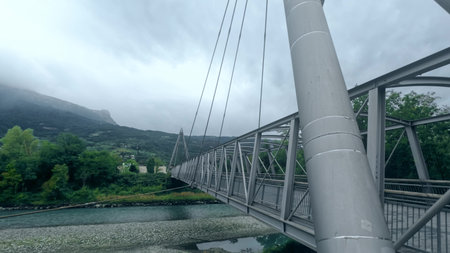 Modern pedestrian bridge crossing the Drac river between Echirolles and Seyssins, France, with the Trois Pucelles mountain peak visible in the backgroundの写真素材