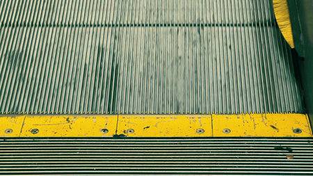 Detailed close-up view of escalator steps with a worn yellow safety marking. Concept of urban...