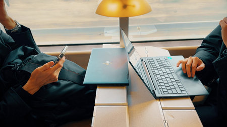 LYON, FRANCE - MARCH 30, 2026. Passengers using HP laptops and smartphone at table inside TER train