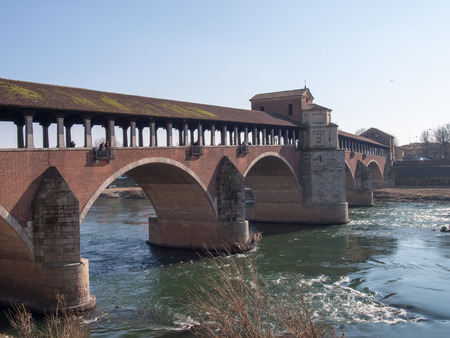 Pavia, Italy - March 8, 2015: Covered bridge over the river Ticino. Very quaint, has five arches and is completely covered with two portals at the ends and a small chapel religious center.の写真素材