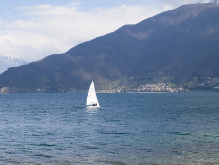 Pianello del Lario, Como - Italy - April 05, 2015: Sailing boat is sailing towards the interior of the lake during the day off Breva the thermal wind typical of Lake Como during the spring / summer.のeditorial素材