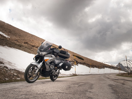 Italy, Apennines Umbria-Marche-Abruzzo - April 24, 2015: Road Trebbio, Bolognola, Sarnano. Panorama of the mountains Sibillini and motorbike parked on the road near the snow.のeditorial素材