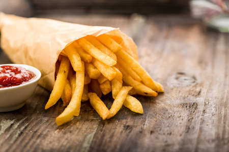 Fresh fried french fries with ketchup on wooden backgroundの写真素材
