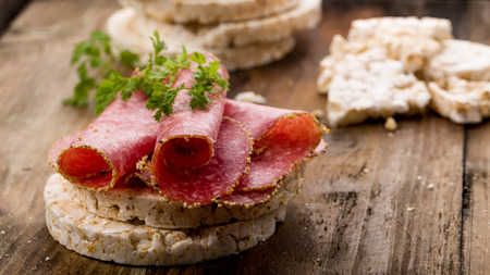 rice wafers topped with salami and fresh herbsの写真素材