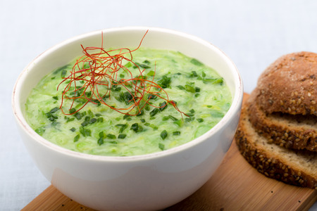 Leek soup with fresh chives sprinkled, chilli and sliced breadの写真素材