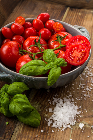 Fresh tomatoes in a bowl with basil and saltの写真素材