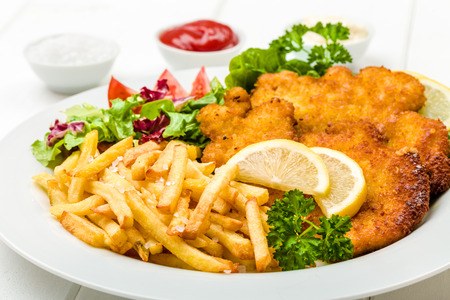 Chicken cutlets with french fries, ketchup, mayo, lemon and saladの写真素材