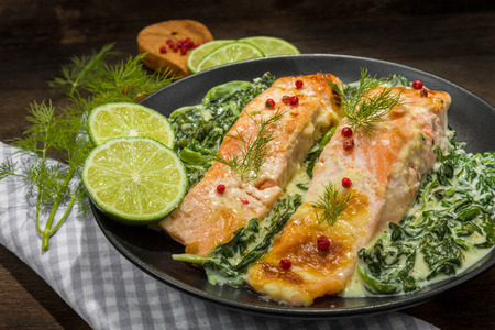 Salmon with spinach and lemon on a wooden surface,の写真素材