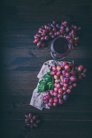 Grapes and a glass of wine on a wooden backgroundの写真素材