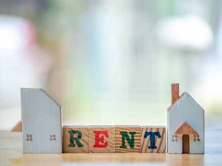 RENT word written cube in front off shopping cart  home on wooden background. Concept for loan, property ladder, financial, mortgage, real estate investment, taxes and bonus.の写真素材