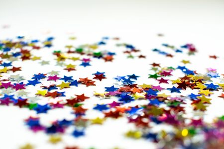 Confetti stars on white background, festive colorful and shiny stars on white background with copy space.の写真素材