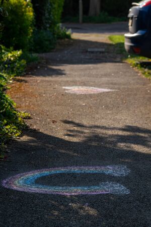 Rainbow and heart drawn by kids on the footpath to up the mood in coronavirus time, colorful chalk drawing of rainbow and clouds made by children from the neighbourhood.の写真素材