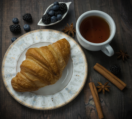 Continental breakfast with a croissant, tea and berries. on a wooden background.の写真素材