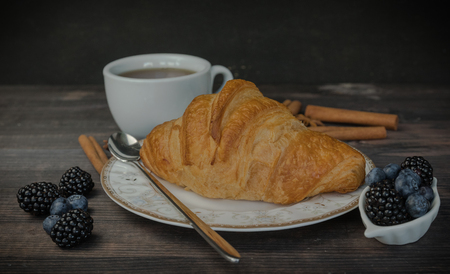 Continental breakfast with a croissant, tea and berries. on a wooden background.の写真素材