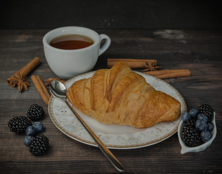 Continental breakfast with a croissant, tea and berries. on a wooden background.の写真素材
