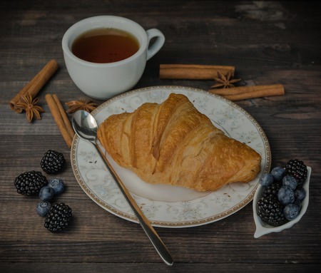 Continental breakfast with a croissant, tea and berries. on a wooden background.の写真素材