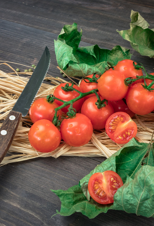 cherry tomatoes on a wooden surface with leaves of wood and hay.の写真素材