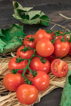 cherry tomatoes on a wooden surface with leaves of wood and hay.の写真素材