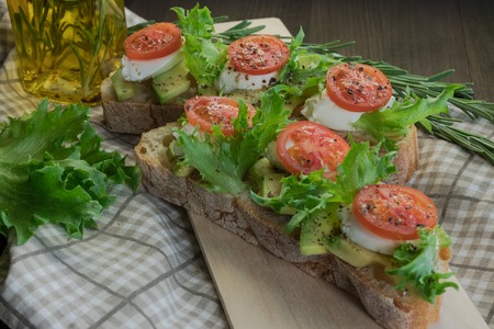Avocado toast, cherry tomato on wooden background. Breakfast with toast avocado, vegetarian food, healthy diet concept.の写真素材