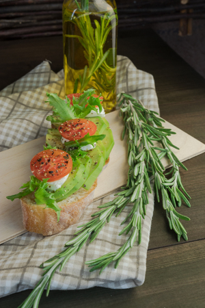 Avocado toast, cherry tomato on wooden background. Breakfast with toast avocado, vegetarian food, healthy diet concept.の写真素材