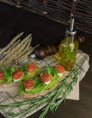 Avocado toast, cherry tomato on wooden background. Breakfast with toast avocado, vegetarian food, healthy diet concept.の写真素材