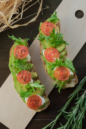 Avocado toast, cherry tomato on wooden background. Breakfast with toast avocado, vegetarian food, healthy diet concept.の写真素材