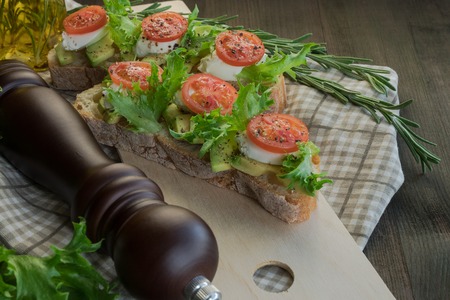 Avocado toast, cherry tomato on wooden background. Breakfast with toast avocado, vegetarian food, healthy diet concept.の写真素材