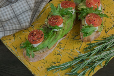 Avocado toast, cherry tomato on wooden background. Breakfast with toast avocado, vegetarian food, healthy diet concept.の写真素材