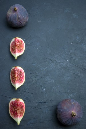 Fresh figs. Food photography. Creative scheme of whole and sliced figs on a dark background,...