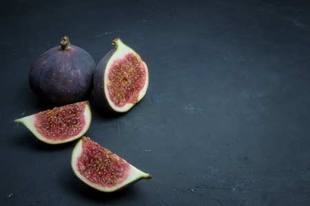 Fresh figs. Food photography. Creative scheme of whole and sliced figs on a dark background, inscribed in a rectangle. Copy spaceの写真素材