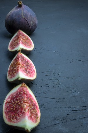 Fresh figs. Food photography. Creative scheme of whole and sliced figs on a dark background,...